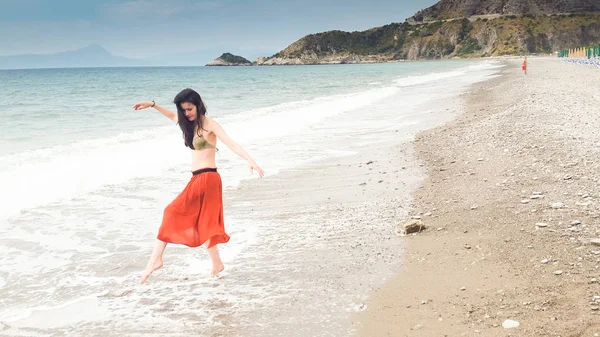Молодая женщина, идущая босиком по берегу — стоковое фото