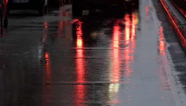 Regenachtige avond met stoplicht weerspiegeld op het asfalt — Stockfoto