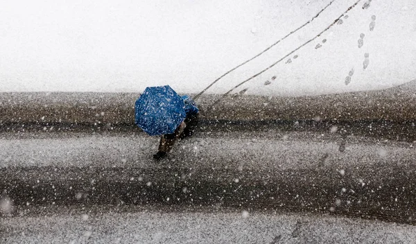 Bad weather with snow and pedestrian under umbrella top view