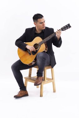 Man plays guitar in white studio with black clothes