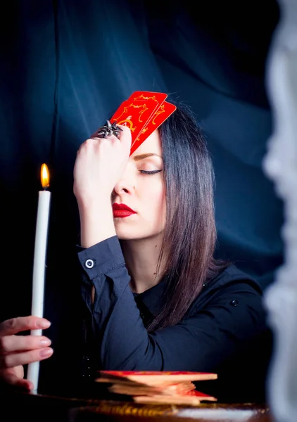 Aynada yansıması içine tarot kartları ve bir mum ile bir kadın görünüyor. Gelecekte, Falcılık, tahmin.