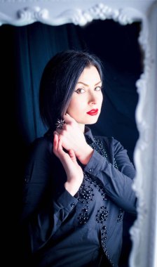  Güzel ince esmer aynada yansıması hayran. Siyah bir gömlek ve kırmızı dudaklar ile bir kız