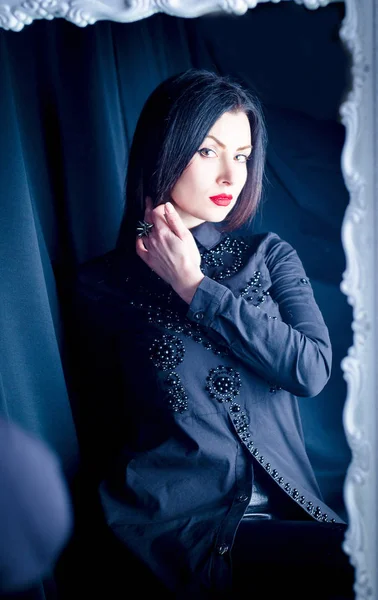  Güzel ince esmer aynada yansıması hayran. Siyah bir gömlek ve kırmızı dudaklar ile bir kız