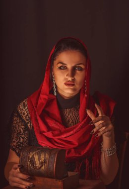 Geleceği tahmin etmek, astral alana ulaşmak. Karanlık bir arka planda elinde kartlar olan falcı delici bakışlarla bakıyor..