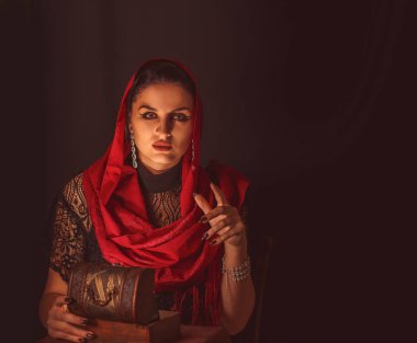 Dişi bir falcı içinde para olan bir kutuyu açar ve keskin bir bakışla bakar. Geleceği tahmin etmek, astral alana ulaşmak.