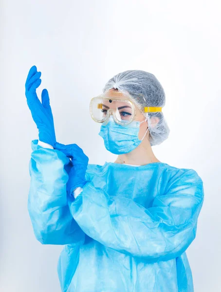 Sağlık çalışanı beyaz arka planda izole edilmiş koruyucu steril kıyafet giyiyor.