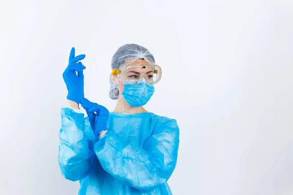 Sağlık çalışanı beyaz arka planda izole edilmiş koruyucu steril kıyafet giyiyor.