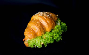 İştah açıcı taze kruvasan. Siyah arka planda marul izole edilmiş.