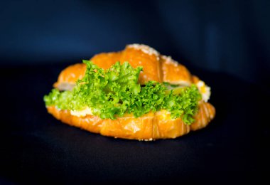 İştah açıcı taze kruvasan. Siyah arka planda marul izole edilmiş.