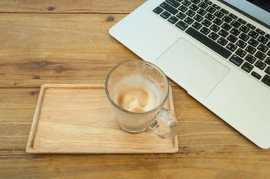 Dizüstü bilgisayar ile ahşap daire üzerinde köpüklü kahve