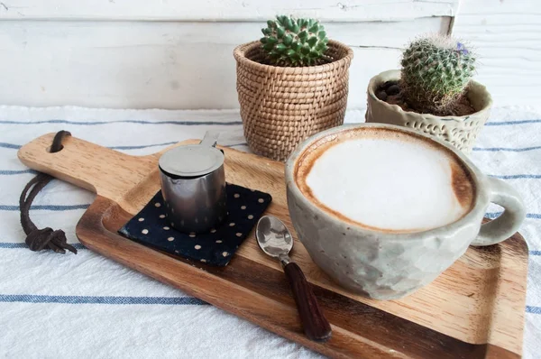 Café quente com leite na mesa de roupas listradas com pouco cacto — Fotografia de Stock