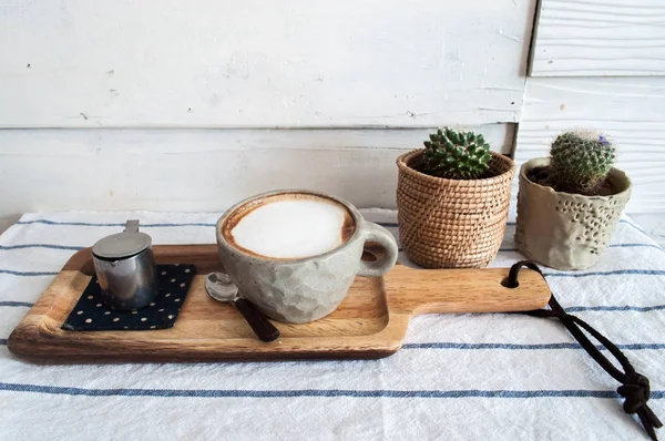 Café Latte quente com pequeno cacto na mesa de roupas listradas — Fotografia de Stock