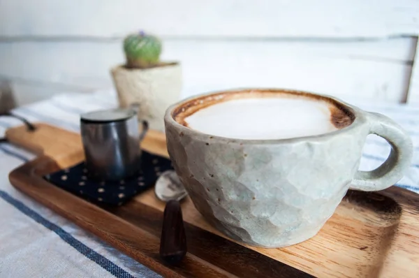 Café quente com leite na mesa de roupas listradas com pequeno cacto no fundo — Fotografia de Stock