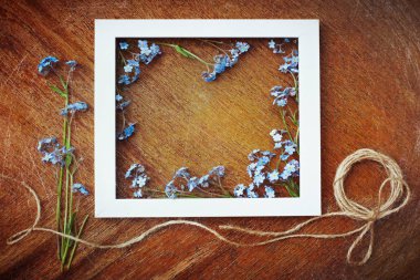 Mavi unutma çiçekler, rustik bir buket ve antika ahşap arka plan üzerinde bulunan beyaz bir çerçeve