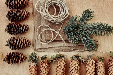 Çam kozalakları ve Kraft kağıt ahşap arka plan üzerinde. Noel hediyeleri el yapımı oluşturma kavramı