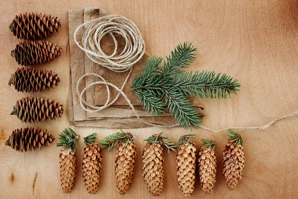 Çam kozalakları ve Kraft kağıt ahşap arka plan üzerinde. Noel hediyeleri el yapımı oluşturma kavramı