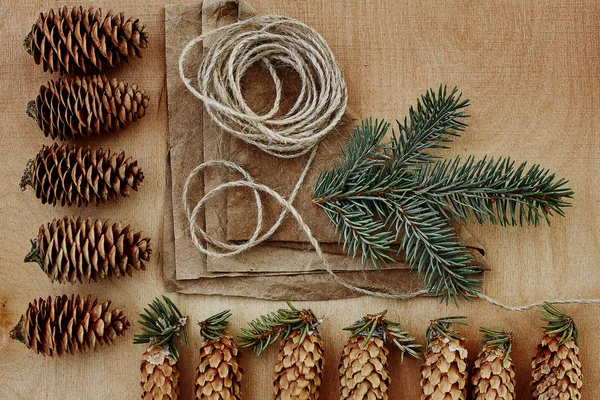 Çam kozalakları ve Kraft kağıt ahşap arka plan üzerinde. Noel hediyeleri el yapımı oluşturma kavramı