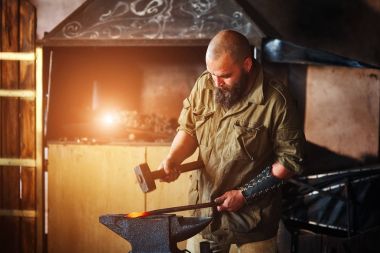 Demirci forge içinde çalışma. Parçalar ve erimiş metal, çekiç ve örs kullanarak silah üretimi.