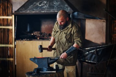 Demirci forge içinde çalışma. Parçalar ve erimiş metal, çekiç ve örs kullanarak silah üretimi.