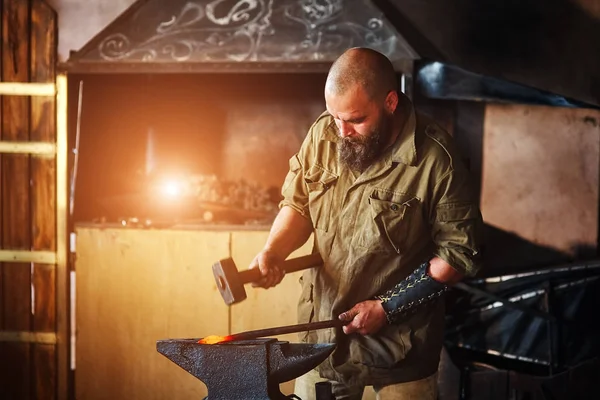 Smid werken in de smidse. Vervaardiging van onderdelen en wapens uit gesmolten metaal, met behulp van de hamer en aambeeld. — Stockfoto