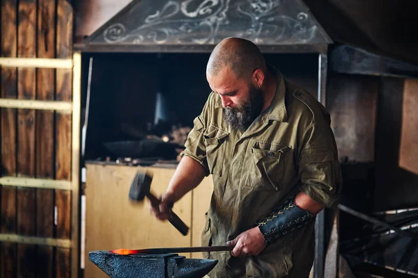 Demirci forge içinde çalışma. Parçalar ve erimiş metal, çekiç ve örs kullanarak silah üretimi.