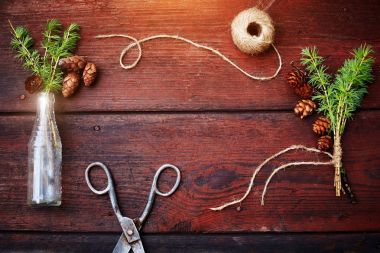 Noel ahşap arka plan. Çam dalları ve koniler vintage bir şişe, eski makas ve kurnaz kordon. Eğitim kavramı Noel için ayarlar. Üstten Görünüm.