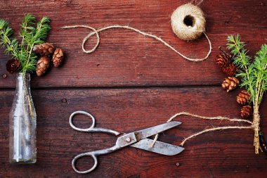 Noel ahşap arka plan. Çam dalları ve koniler vintage bir şişe, eski makas ve kurnaz kordon. Eğitim kavramı Noel için ayarlar. Üstten Görünüm.