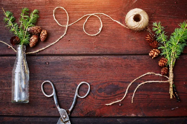 Noel ahşap arka plan. Çam dalları ve koniler vintage bir şişe, eski makas ve kurnaz kordon. Eğitim kavramı Noel için ayarlar. Üstten Görünüm.