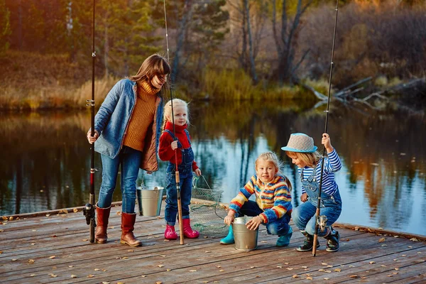 Niños pescando viendo la captura de un amigo. Muelle de madera, el otoño Tiempo soleado — Foto de Stock