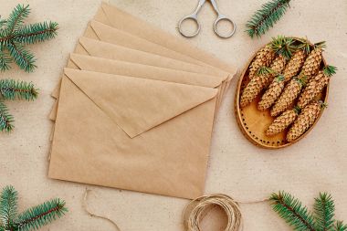 Noel hediyeleri ve harfler el yapımı ve onlar için gerekli her şey. Zarf Kraft kağıt, makas, çam kozalakları ve jüt kordon. Üstten Görünüm. Sadelik kavramı