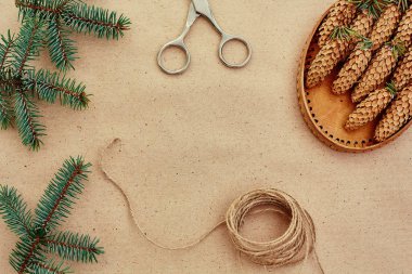 El yapımı yılbaşı hediyeleri ve onlar için arka plan Kraft kağıt, makas, çam kozalakları ve jüt Kordon üzerinde gerekli her şey. Üstten Görünüm. Sadelik kavramı