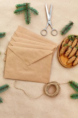 Noel hediyeleri ve harfler el yapımı ve onlar için gerekli her şey. Zarf Kraft kağıt, makas, çam kozalakları ve jüt kordon. Üstten Görünüm. Sadelik kavramı