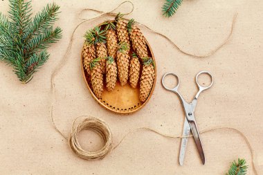 El yapımı yılbaşı hediyeleri ve onlar için arka plan Kraft kağıt, makas, çam kozalakları ve jüt Kordon üzerinde gerekli her şey. Üstten Görünüm. Sadelik kavramı