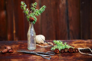 Noel ahşap arka plan. Çam dalları ve koniler vintage bir şişe, eski makas ve kurnaz kordon. Eğitim kavramı Noel için ayarlar. 