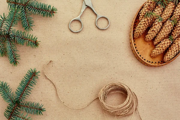 El yapımı yılbaşı hediyeleri ve onlar için arka plan Kraft kağıt, makas, çam kozalakları ve jüt Kordon üzerinde gerekli her şey. Üstten Görünüm. Sadelik kavramı
