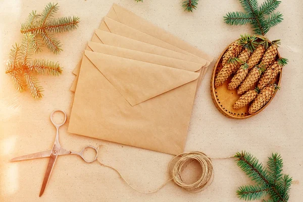 Noel hediyeleri ve harfler el yapımı ve onlar için gerekli her şey. Zarf Kraft kağıt, makas, çam kozalakları ve jüt kordon. Üstten Görünüm. Sadelik kavramı