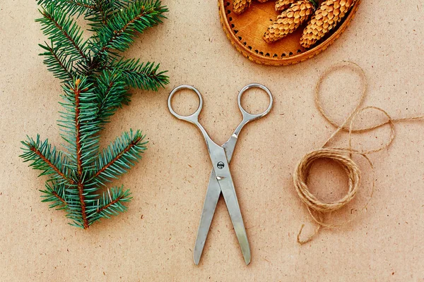 El yapımı yılbaşı hediyeleri ve onlar için arka plan Kraft kağıt, makas, çam kozalakları ve jüt Kordon üzerinde gerekli her şey. Üstten Görünüm. Sadelik kavramı