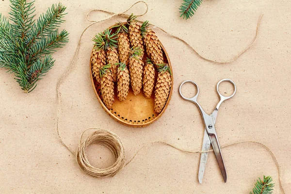 El yapımı yılbaşı hediyeleri ve onlar için arka plan Kraft kağıt, makas, çam kozalakları ve jüt Kordon üzerinde gerekli her şey. Üstten Görünüm. Sadelik kavramı