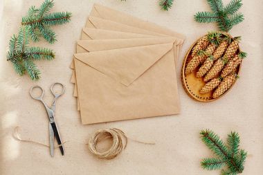 Noel hediyeleri ve harfler el yapımı ve onlar için gerekli her şey. Zarf Kraft kağıt, makas, çam kozalakları ve jüt kordon. Üstten Görünüm. Sadelik kavramı