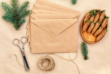 Noel hediyeleri ve harfler el yapımı ve onlar için gerekli her şey. Zarf Kraft kağıt, makas, çam kozalakları ve jüt kordon. Üstten Görünüm. Sadelik kavramı