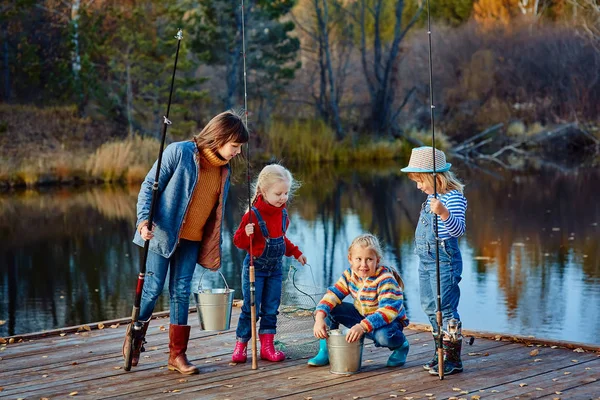 Четыре маленькие девочки ловят рыбу на деревянном понтоне — стоковое фото