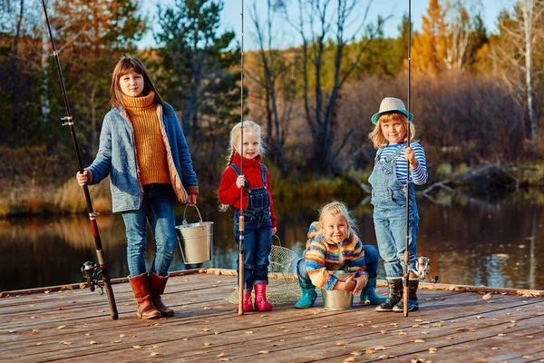 Чотири маленькі дівчата ловлять рибу на дерев'яному понтоні — стокове фото