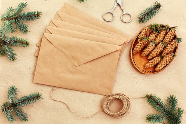 Noel hediyeleri ve harfler el yapımı ve onlar için gerekli her şey. Zarf Kraft kağıt, makas, çam kozalakları ve jüt kordon. Üstten Görünüm. Sadelik kavramı