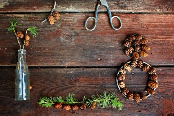 Fundo de Natal em velhas tábuas de madeira com elemento decorativo na forma de uma figura oito, tesoura antiga, garrafa antiga e cones — Fotografia de Stock