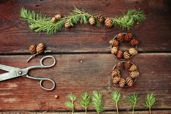 Fundo de Natal em velhas tábuas de madeira com elemento decorativo na forma de uma figura oito, tesouras antigas e cones de lariço — Fotografia de Stock