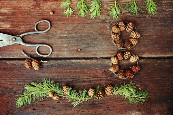 Fundo de Natal em velhas tábuas de madeira com elemento decorativo na forma de uma figura oito, tesouras antigas e cones de lariço — Fotografia de Stock