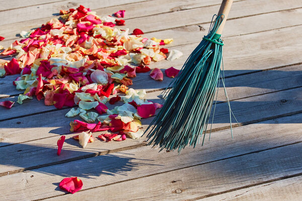 Multicolored rose petals are swept with a broom after the weddin