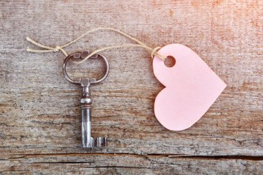 Tahta bir masada kalbi olan eski güzel bir anahtar. Metnin için yeri olan kalp anahtarlığı. Tepeden Bakış. Valentine.