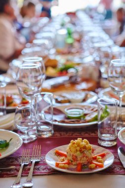 Uzun bir masada bir grup insan ve yiyecek. Unutulmaz tarihlerin ya da tatillerin ortak kutlaması konsepti.