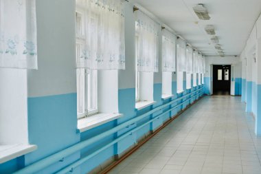 Bir devlet okulu, mavi duvarlı uzun boş bir koridor.